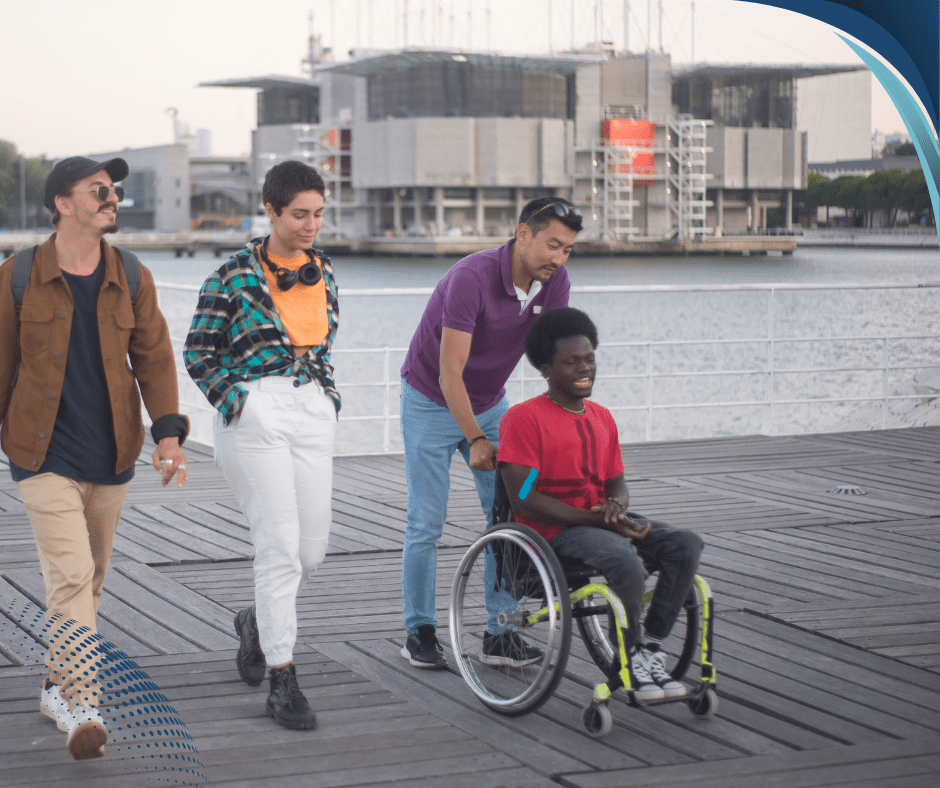 guy in wheelchair with support worker and friends going for a walk near the ocean as part of their social and community ndis budget spend. Social and Community NDIS